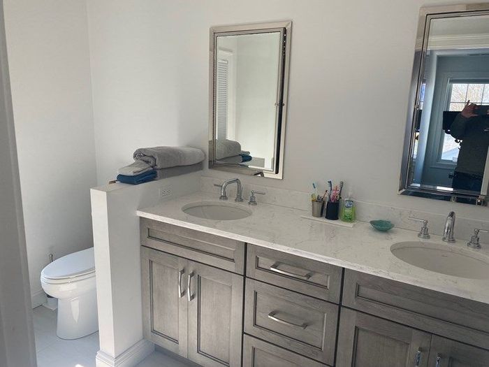 A bathroom with two sinks , a toilet and a mirror.