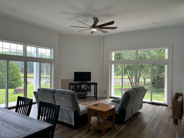 A living room with a couch , table , chairs and a ceiling fan.