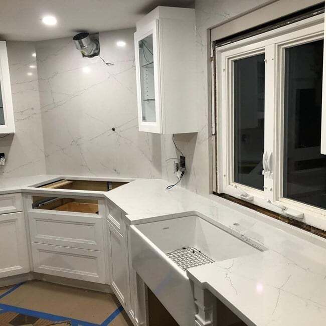 A kitchen with white cabinets , a sink , and a window.