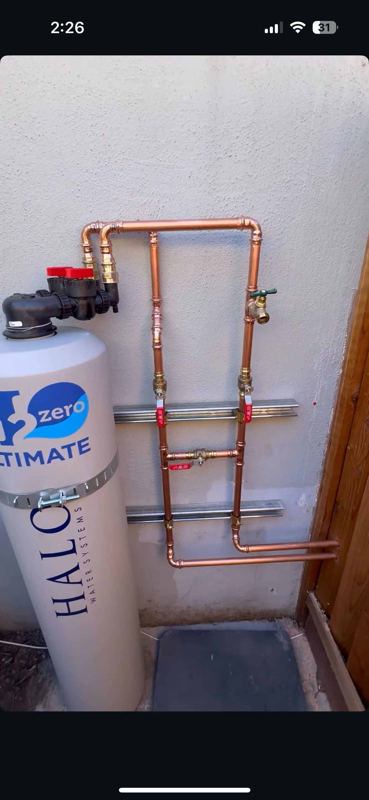 Copper pipes connected to a water heater next to a wall in a utility area