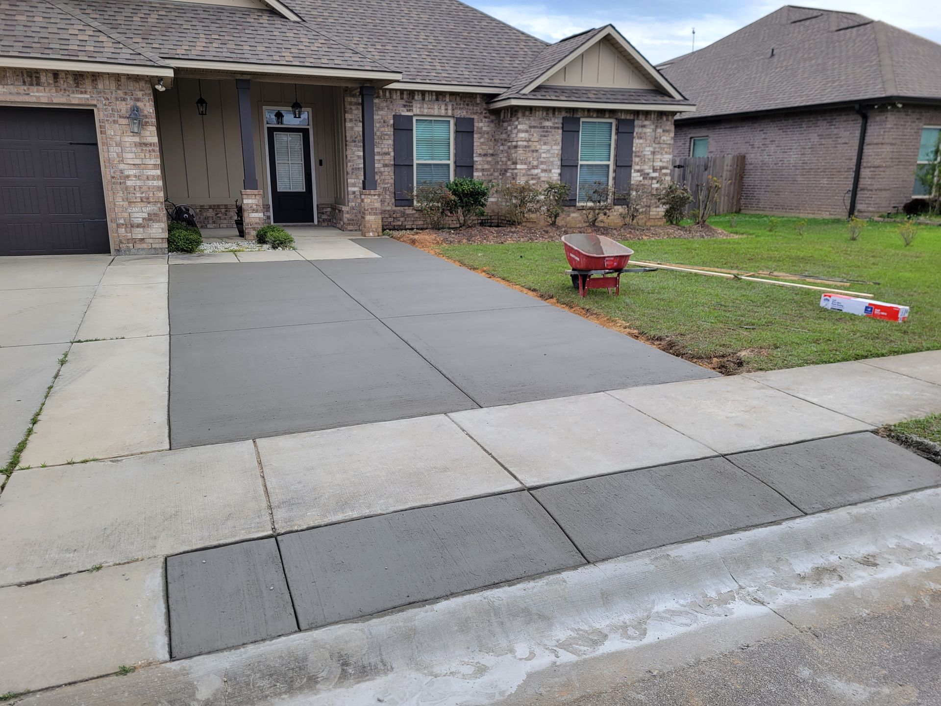 A freshly poured concrete driveway extension with a new curb cut and sidewalk transition in front of a residential home.