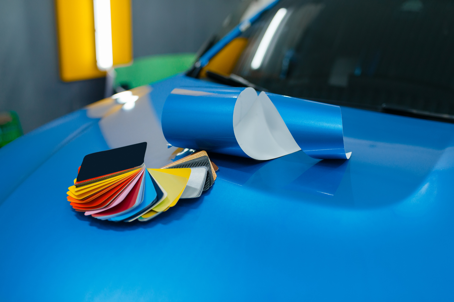 Person wearing gloves cleaning the inside of a car window with a blue cloth.