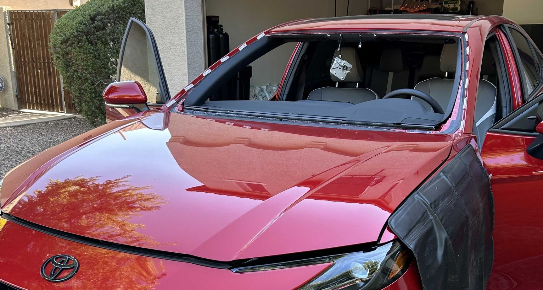 Windshield removed from a red car with the ADAS not attached to the windshield.