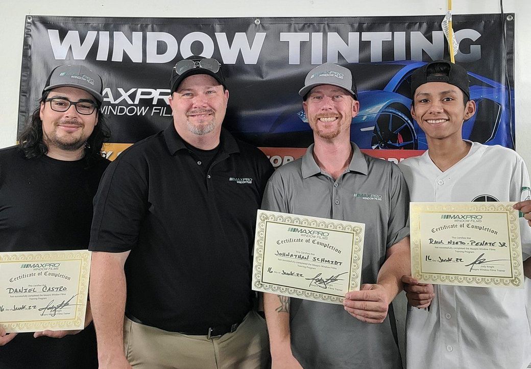 Window Tinting Service Certified window tint installers standing in front of a window tinting sign.