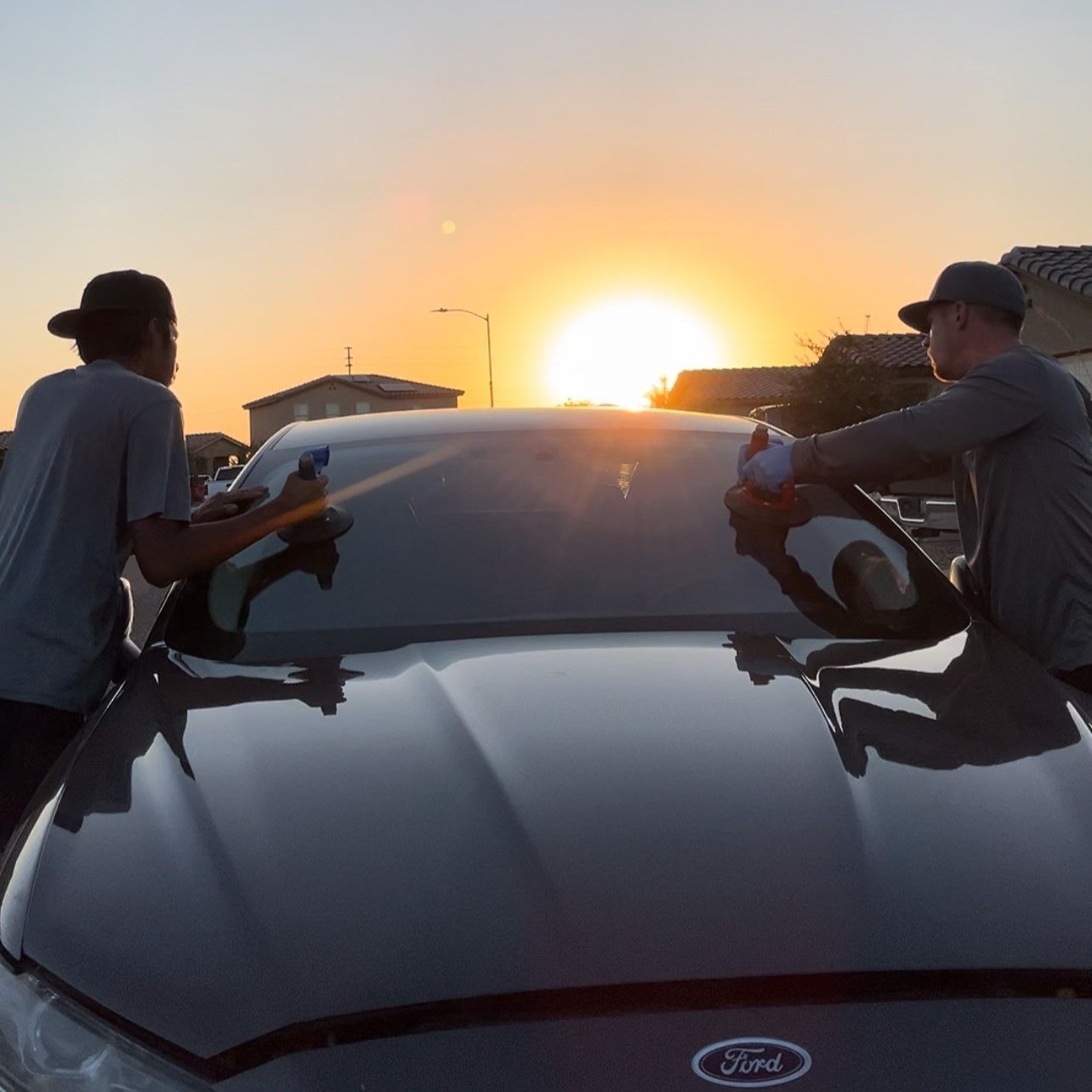 Windshield replacement with a sunrise behind the car.