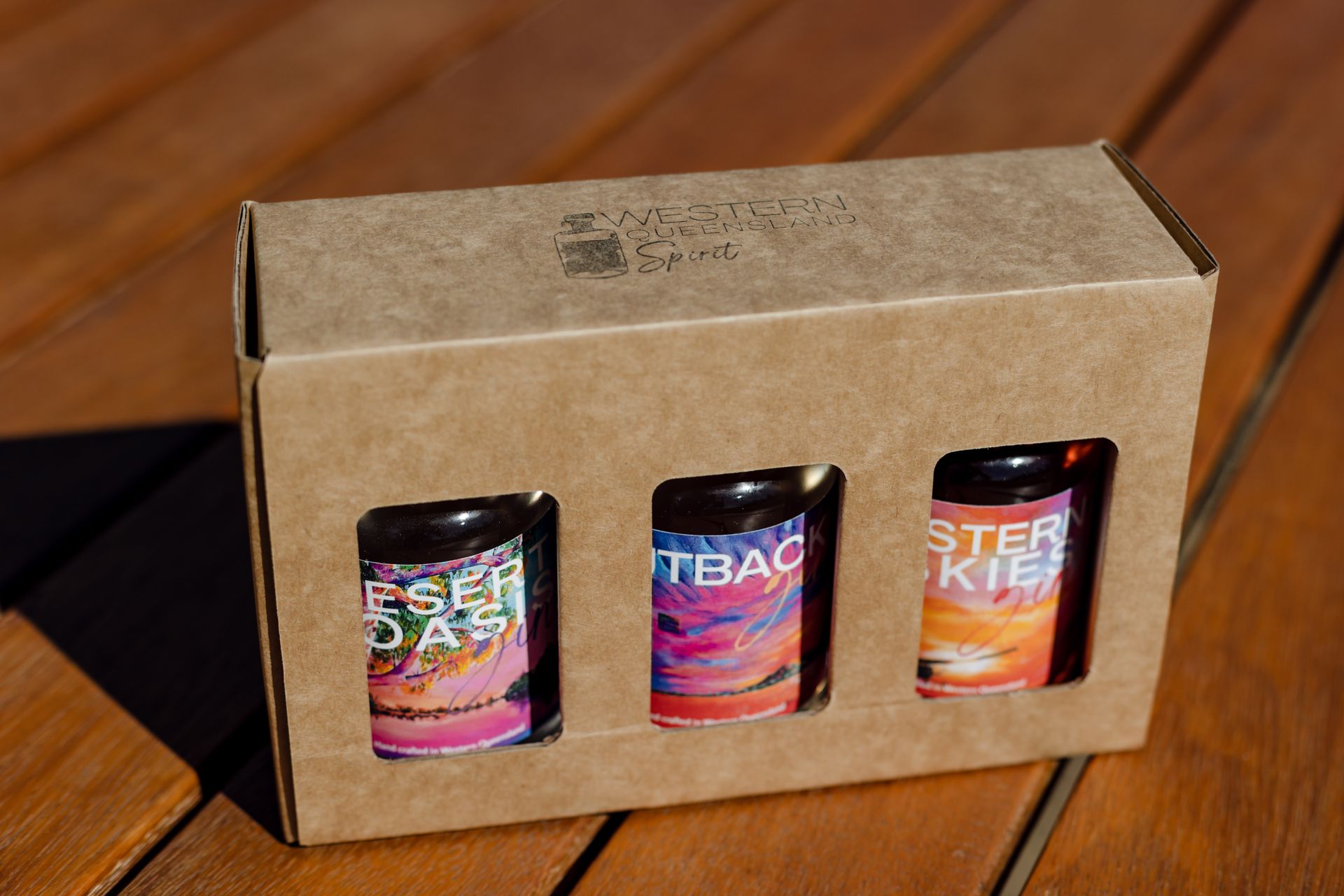 Three bottles of beer are in a box on a wooden table.