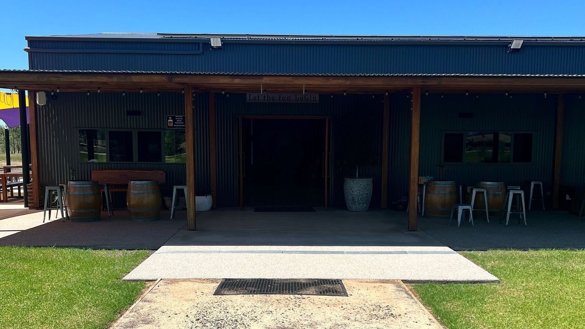 A large building with a porch and barrels in front of it.