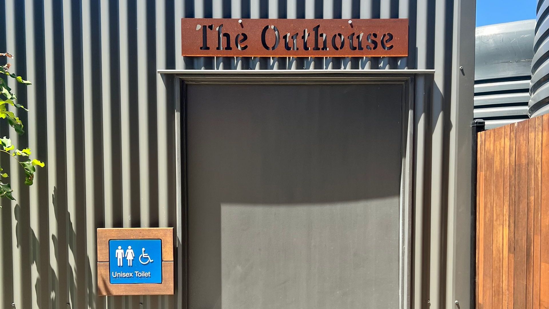 The outside of a building with a sign that says the Outhouse