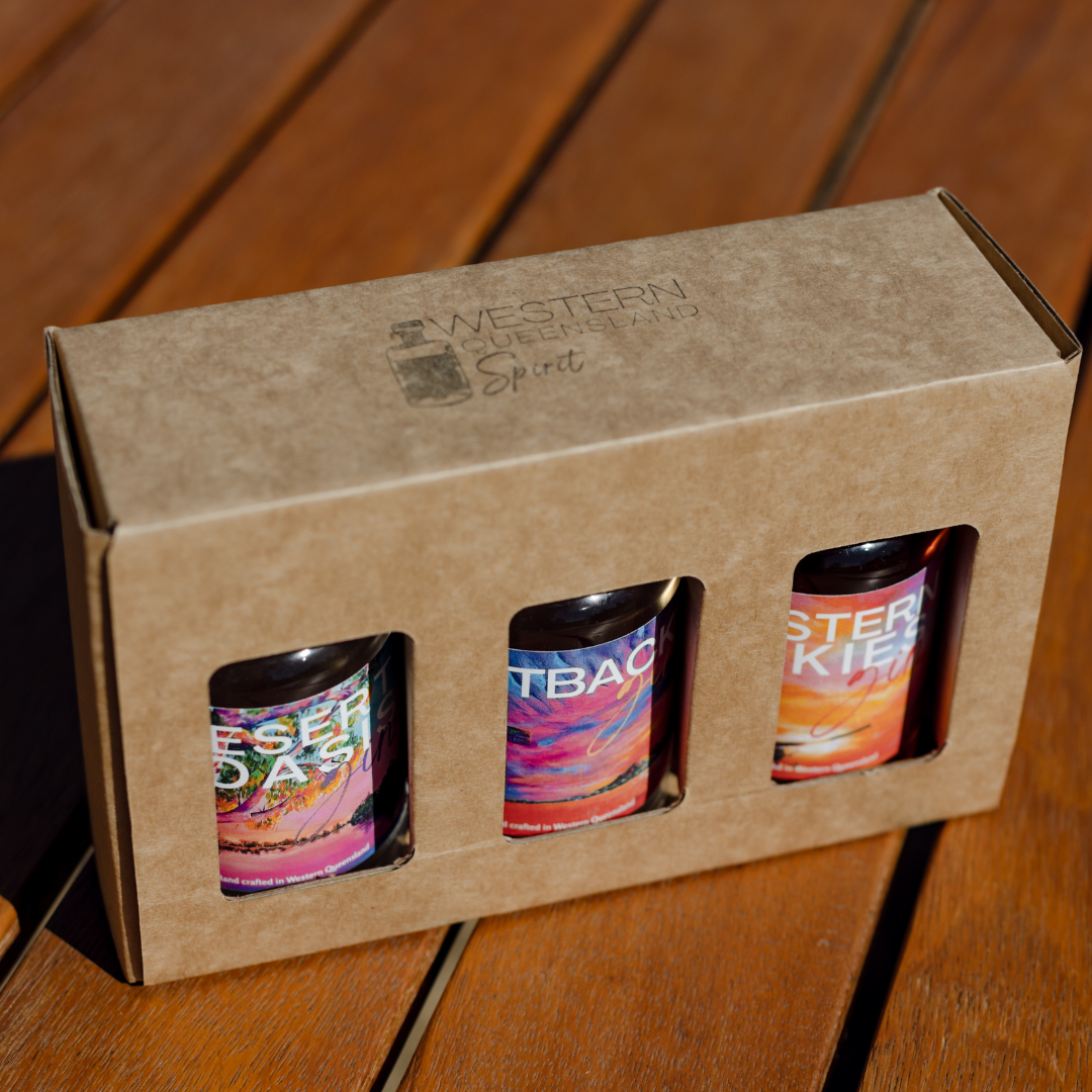 A box of three bottles of alcohol is sitting on a wooden table.