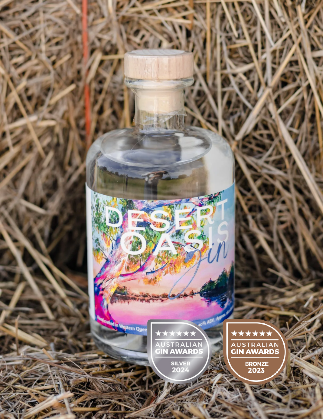 a bottle of desert oasis gin is sitting on top of a pile of hay .