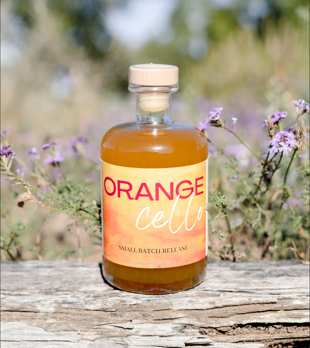 A bottle of orangecello is sitting on a piece of wood.