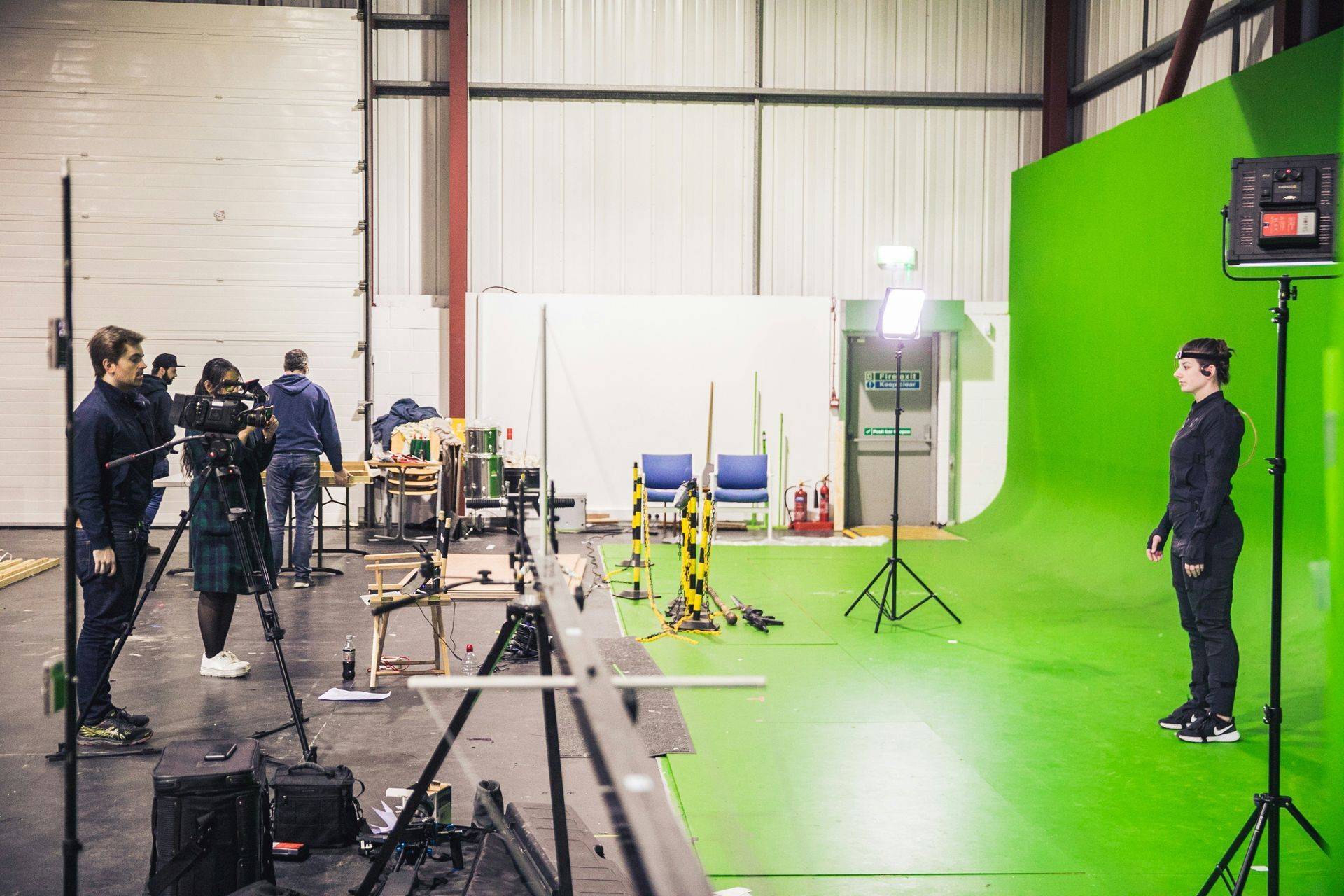 Film studio with green screen wall, camera equipment, and crew on a soundstage