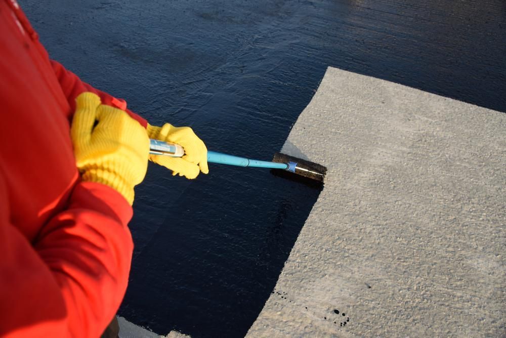 A Person Wearing Yellow Gloves Is Holding A Broom Over A Concrete Surface — Paint & Trade Supplies Lismore In Goonellabah, NSW