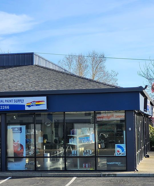 Blue-roofed storefront with large glass windows and a small sign, seen on a sunny street corner.