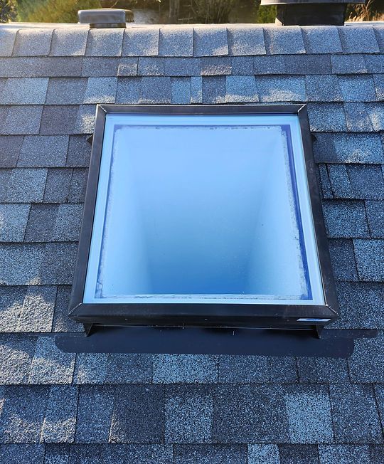 Blue skylight window on a gray shingle roof.
