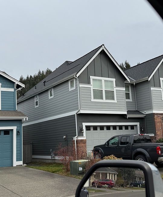 Gray two-story suburban house with white trim, garage, and parked black pickup truck in the driveway