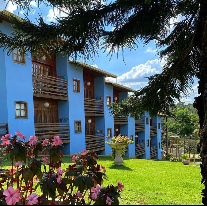 Um prédio azul com varandas e flores na frente