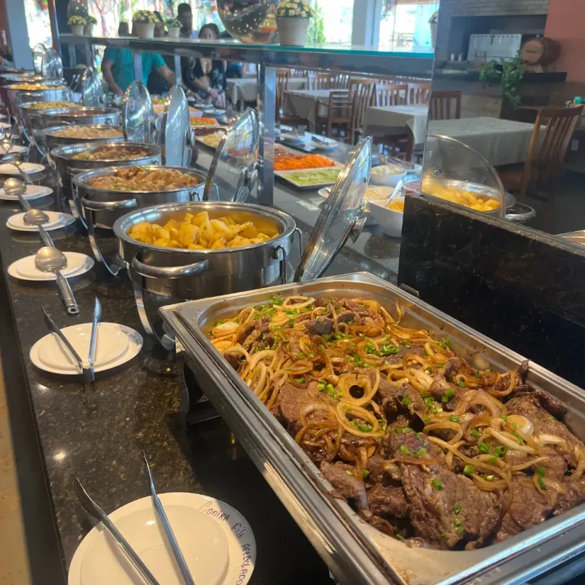 Uma fila de buffet com uma bandeja de carne e macarrão