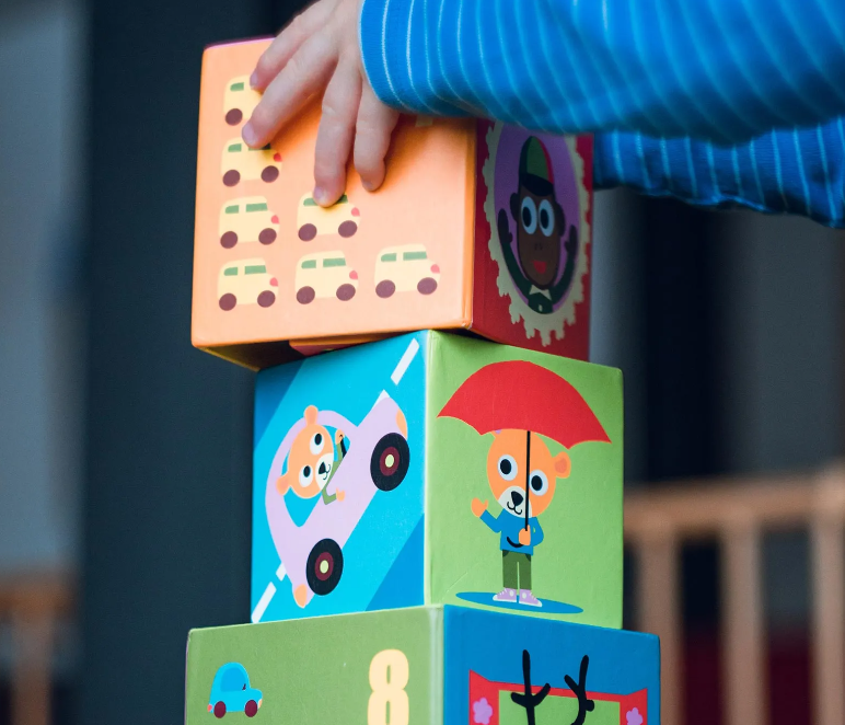 Child stacking colorful wooden blocks outdoors