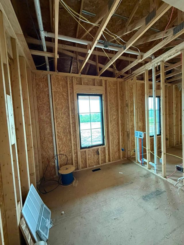 Framed room under construction with exposed studs, ceiling joists, and a window letting in daylight.