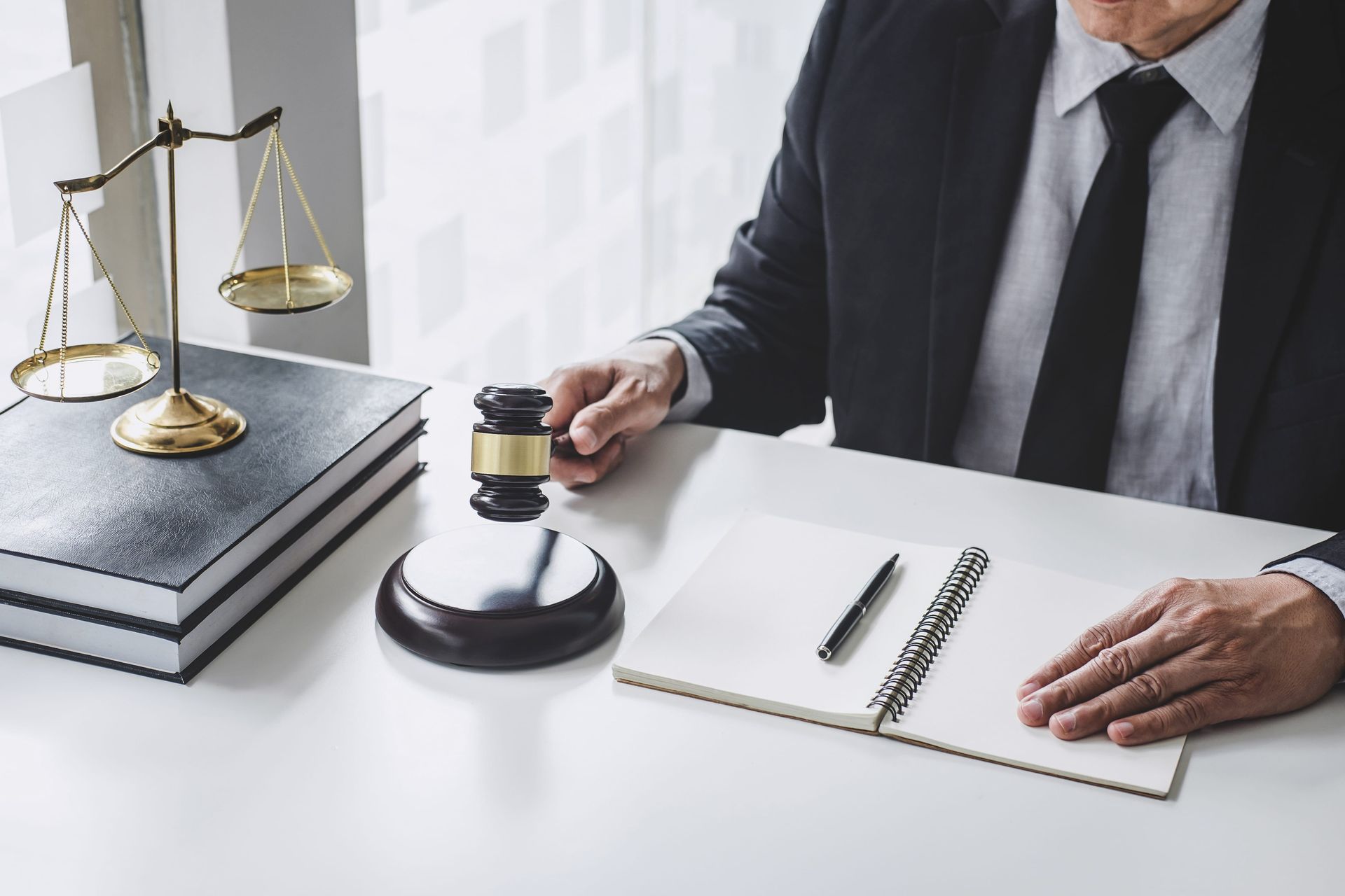 Lawyer pressing a gavel beside scales of justice and a document on a desk