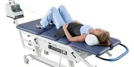 Person lying on a blue examination table connected to a medical imaging machine