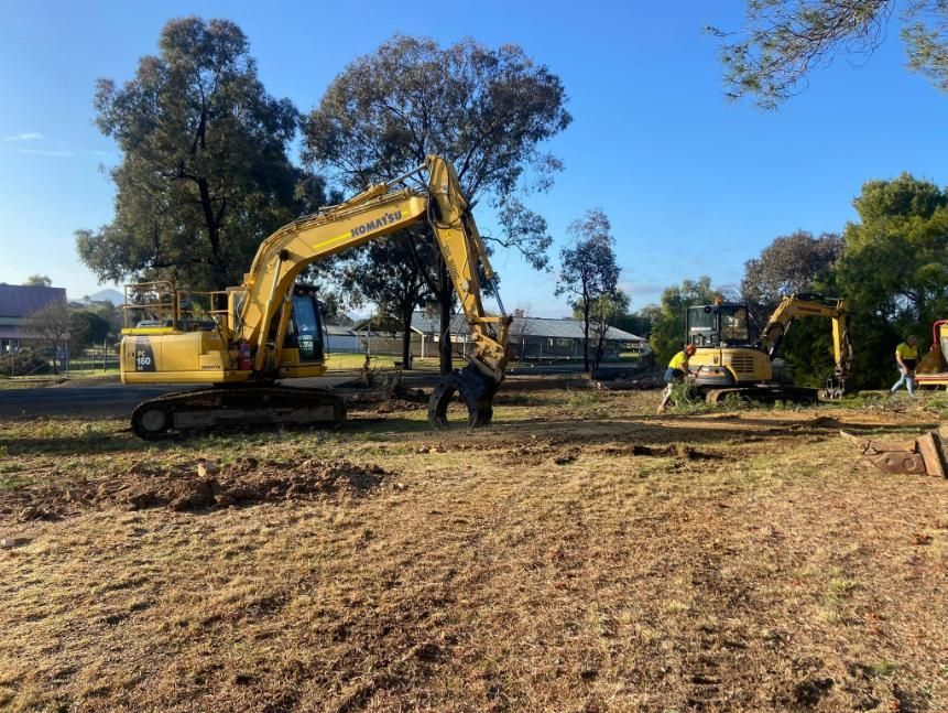 A Yellow Excavator Is Sitting on Top of A Dirt Field — Mudgee Tree Services in Eurunderee, NSW