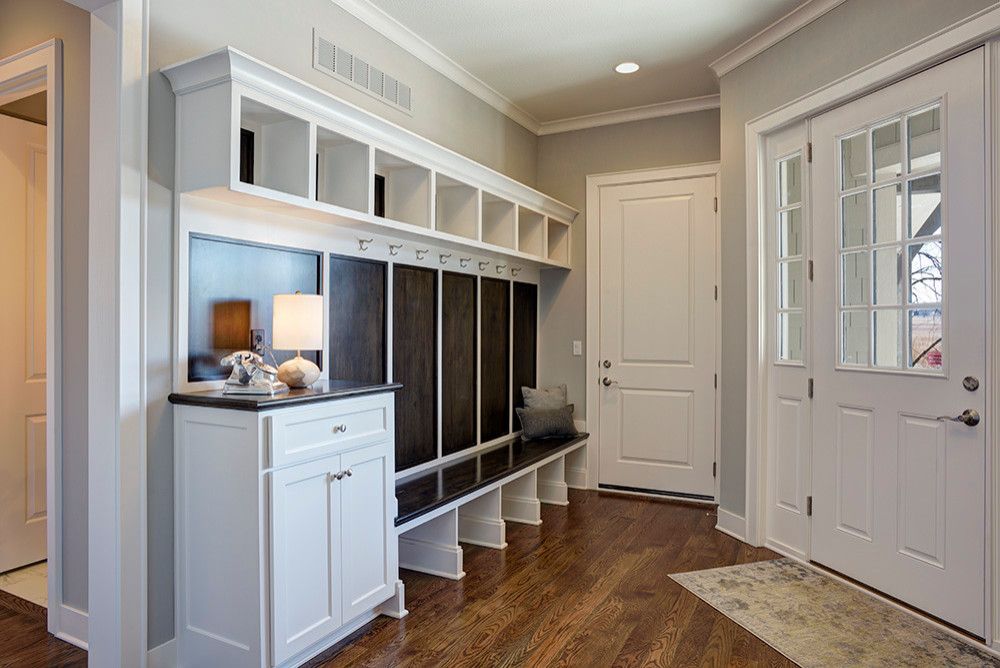 A hallway with hardwood floors, white cabinets, and a bench