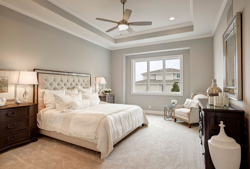 A bedroom with a bed, dresser, chair and ceiling fan