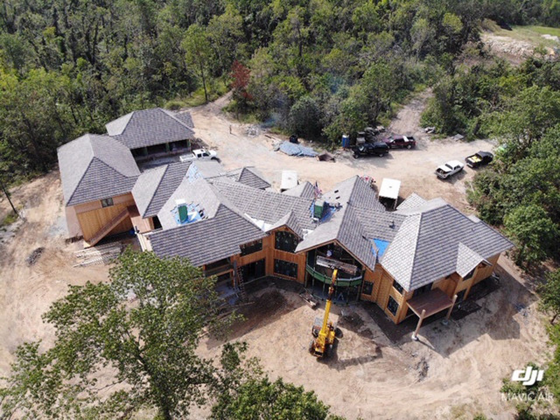 An aerial view of a large house under construction in the middle of a forest