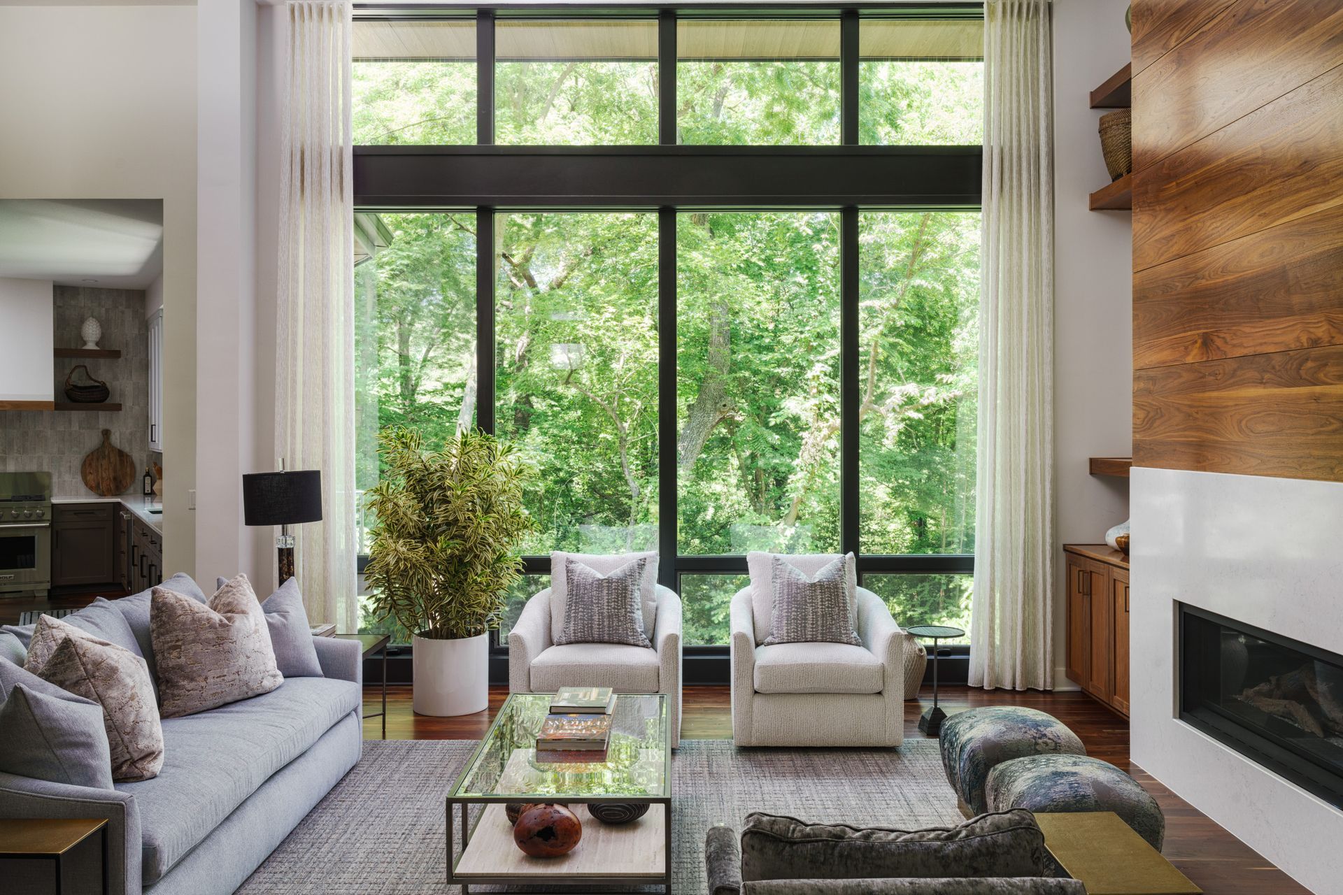 A living room with a couch, chairs, coffee table and large windows