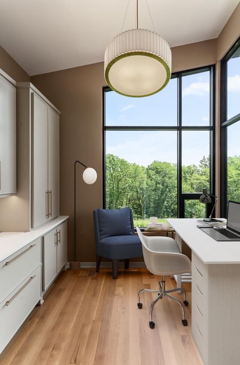 A home office with a desk , chair and large window.