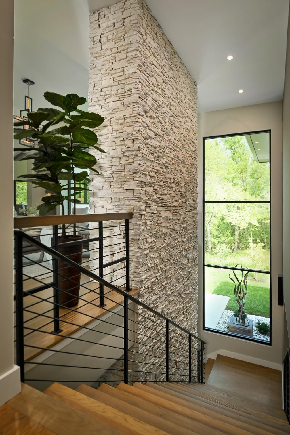A staircase in a house with a brick wall and a large window.