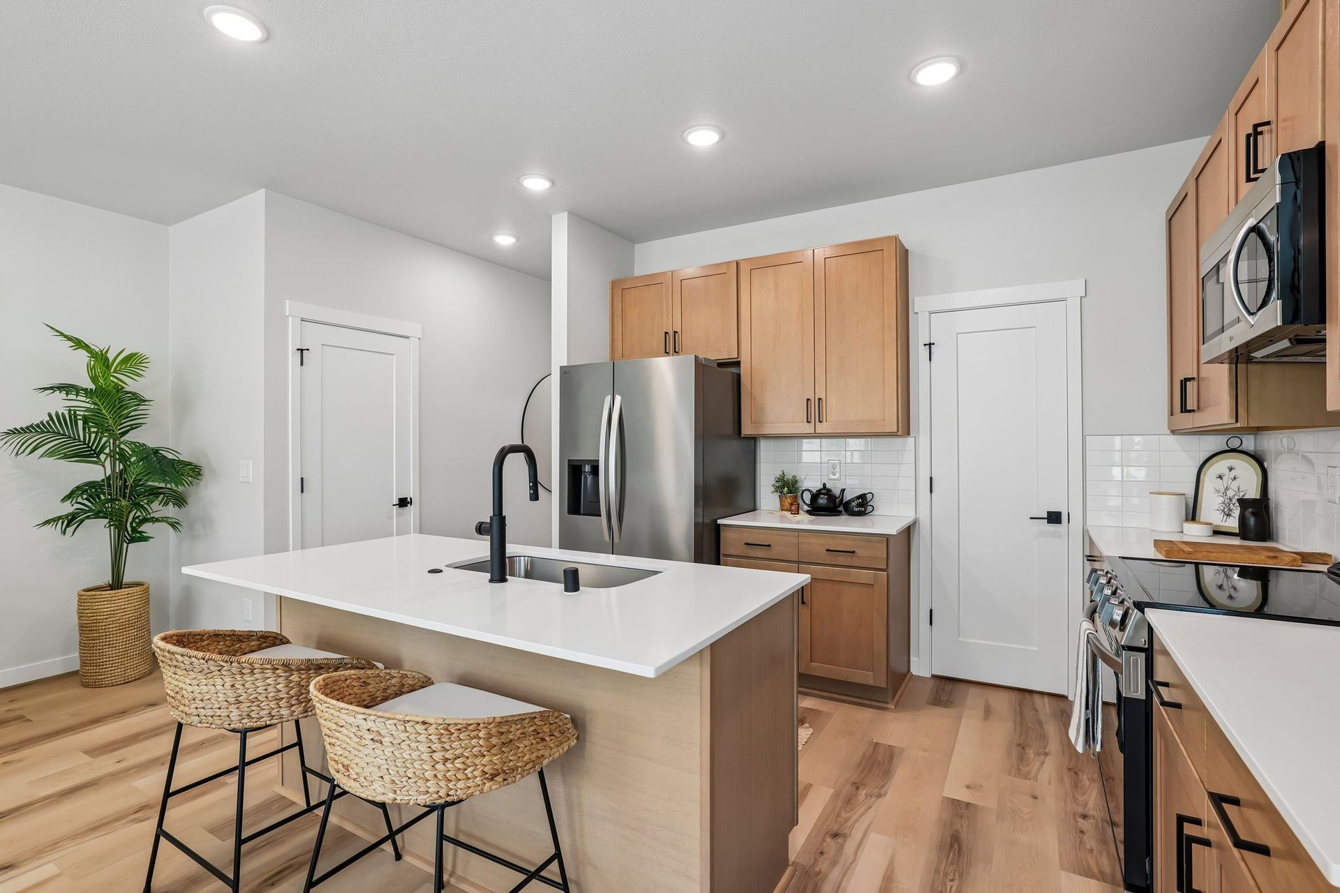 Modern kitchen with white island, wood cabinets, stainless fridge, bar stools, and pendant lighting