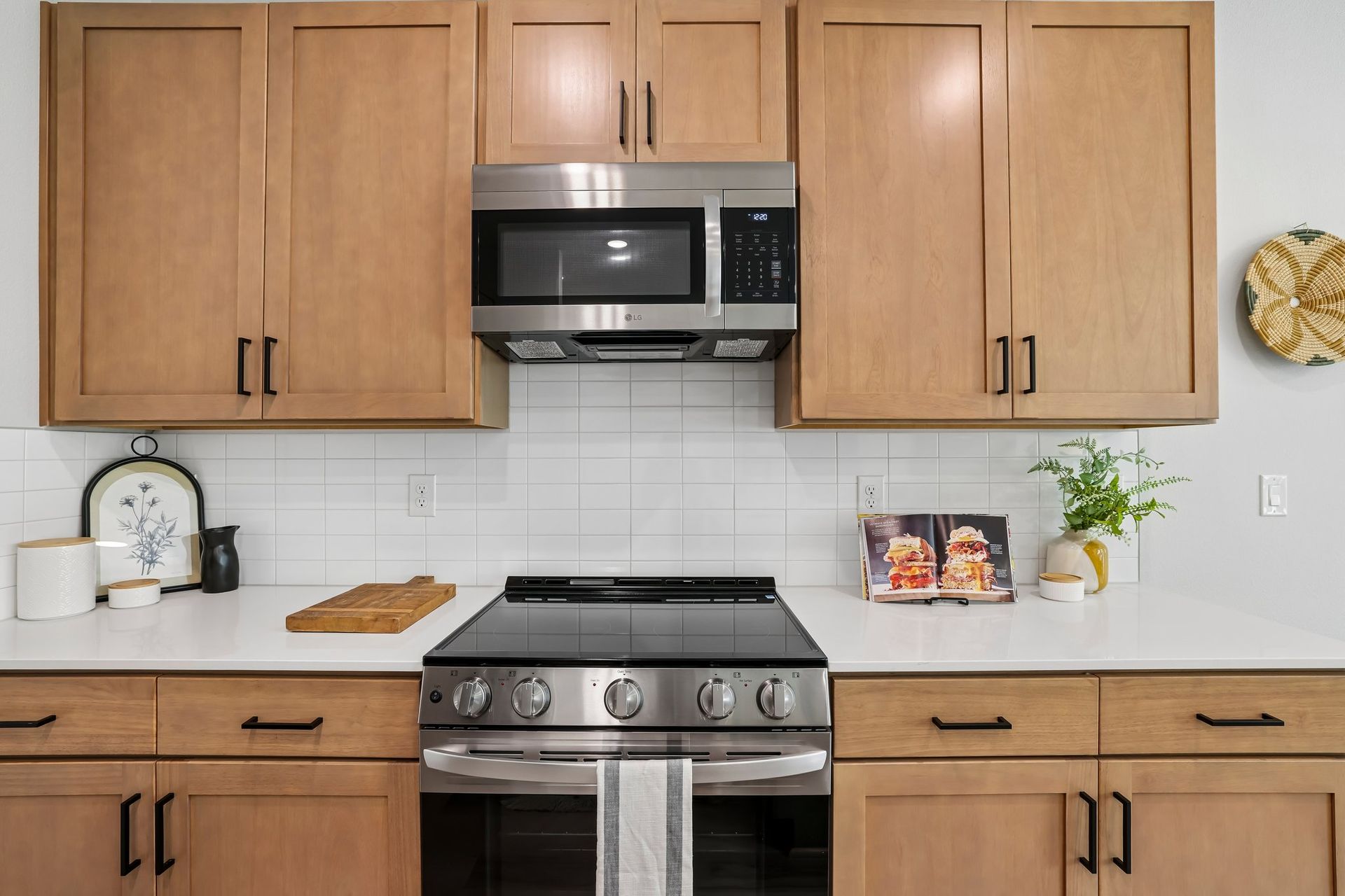 Modern kitchen with wooden cabinets, stainless steel stove and microwave, and light countertop decor