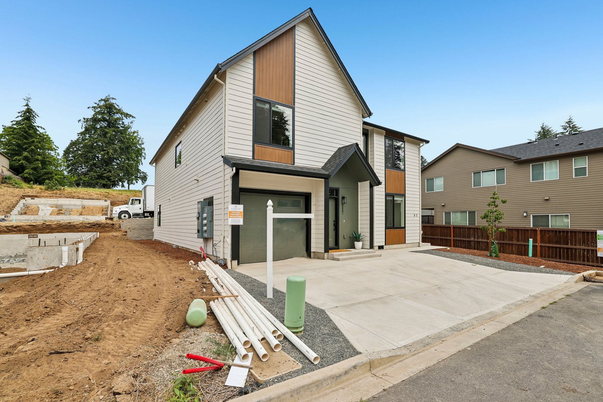Modern two-story house with a driveway, front porch, and unfinished landscaping
