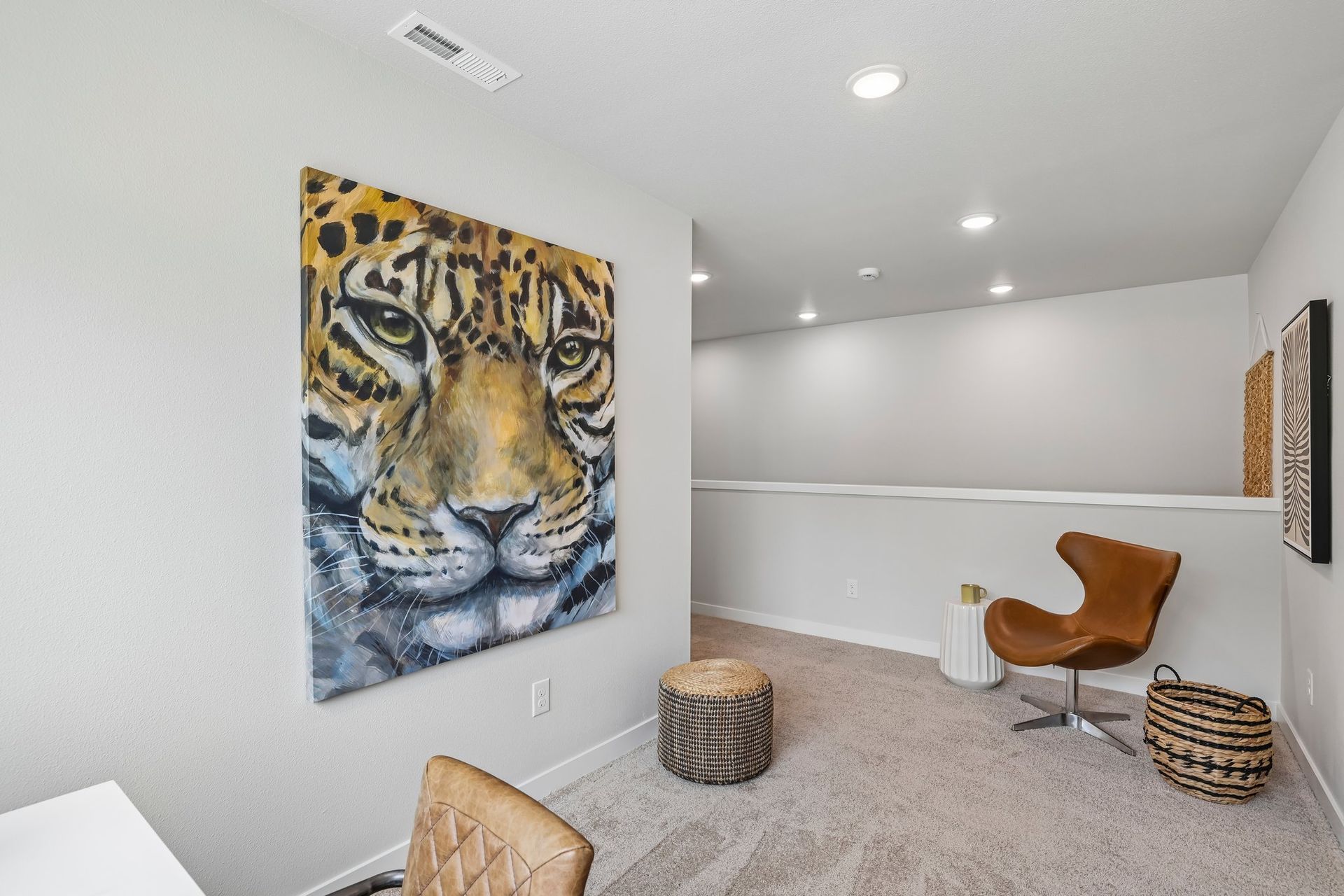 Bright modern room with tiger artwork, beige carpet, orange chair, and decorative basket stool.