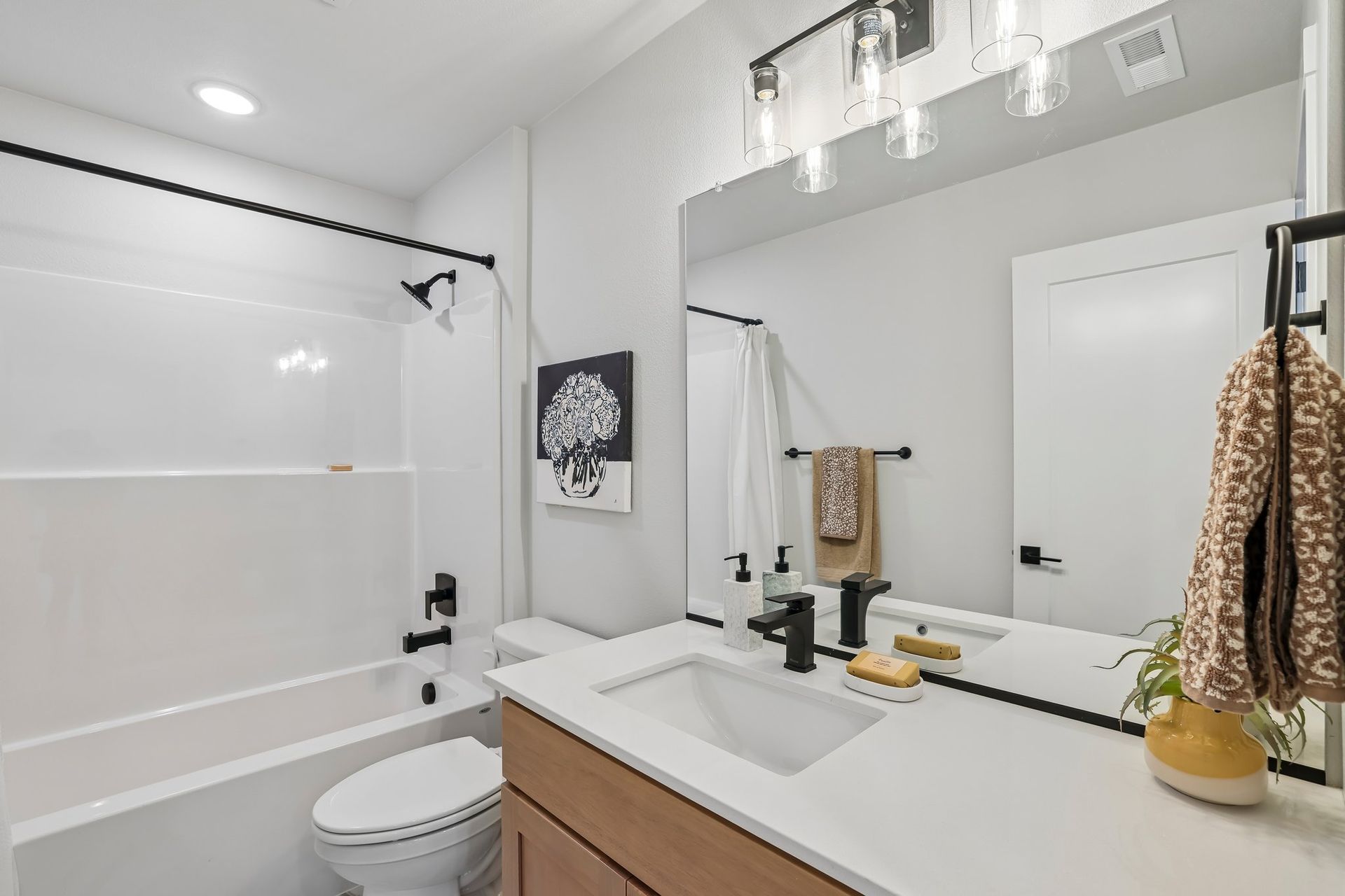 Bright modern bathroom with white tub, vanity, and large mirror
