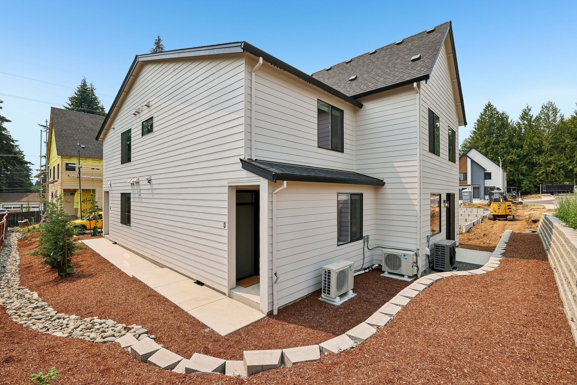 New white two-story house with dark roof and gravel landscaping under construction