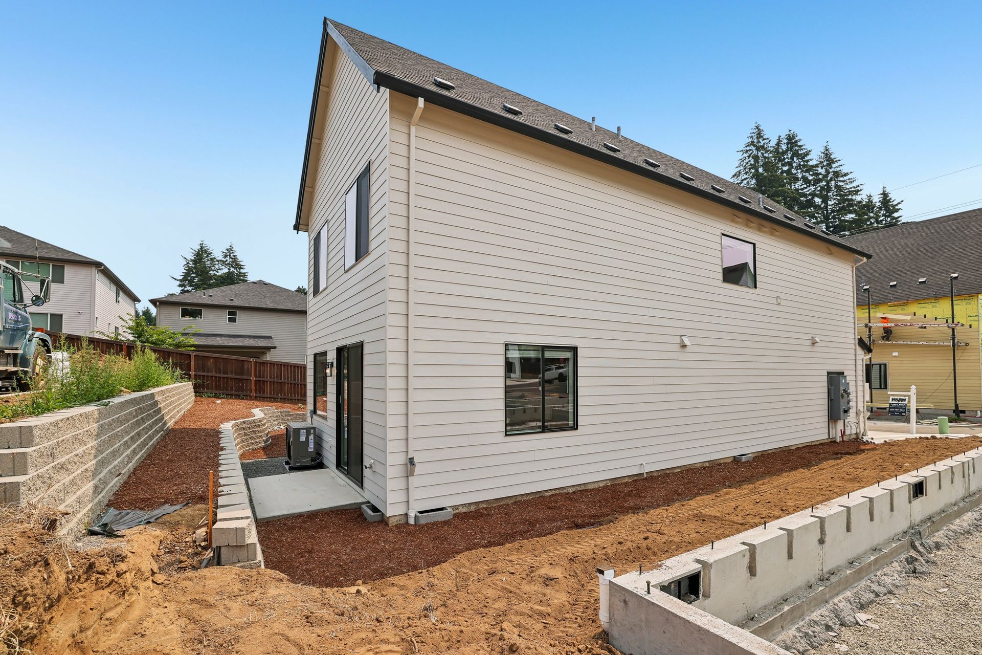 New white two-story house with black-trim windows and unfinished landscaping in a residential yard