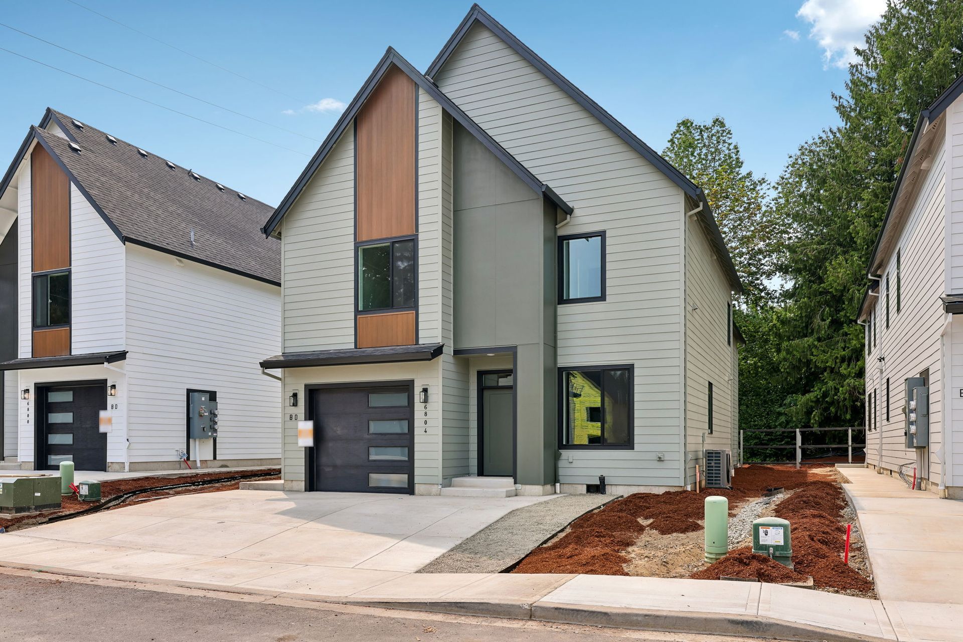 Modern two-story townhouse with a gray garage, white siding, and a front concrete driveway