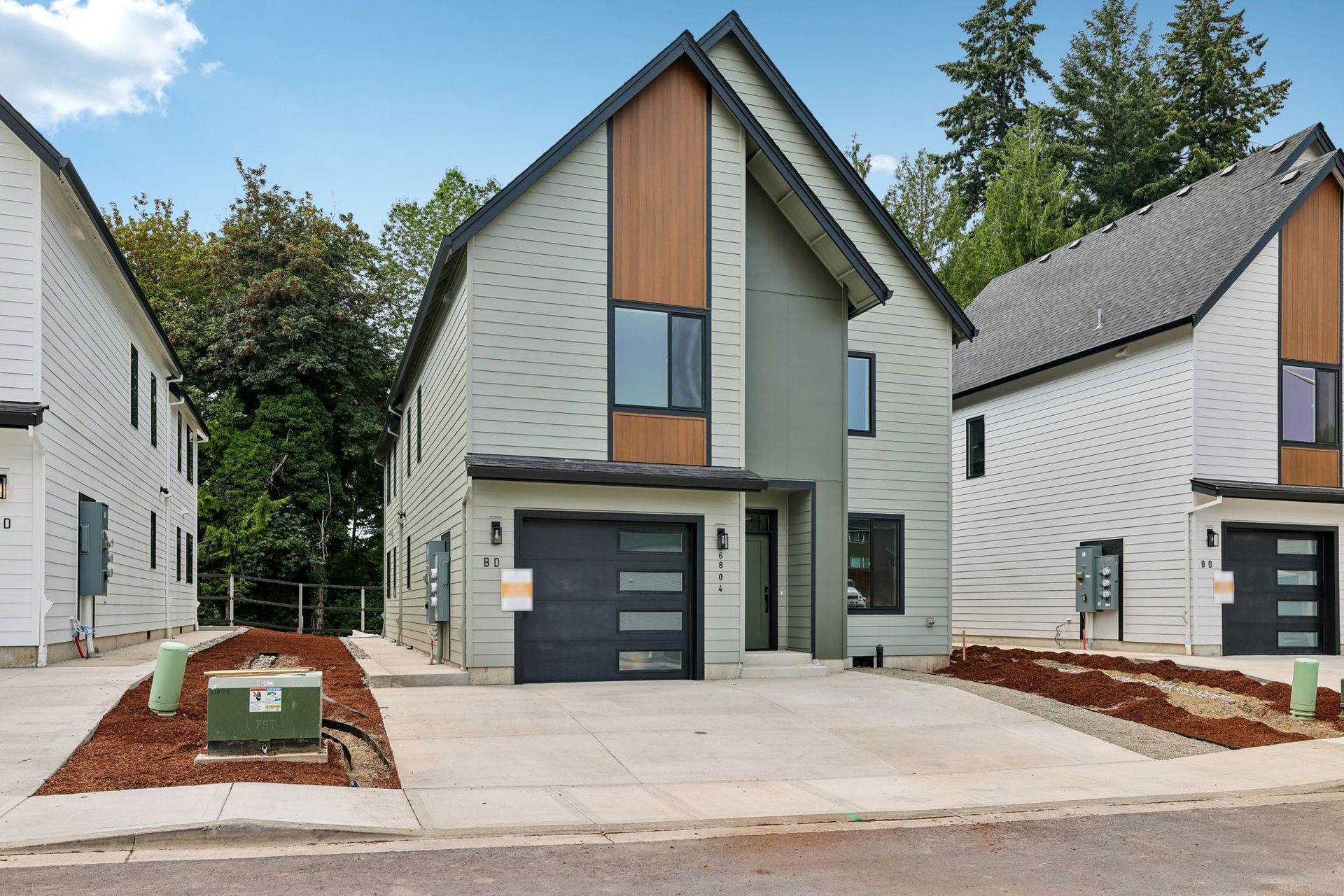 Modern gray house with steep roof, wood accents, garage, and driveway in a residential neighborhood