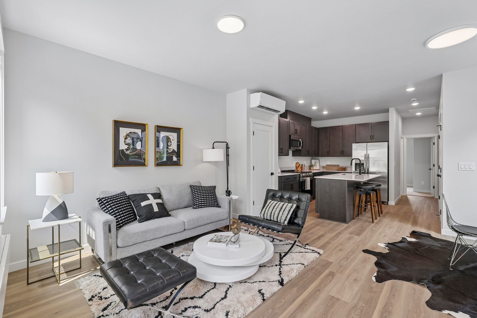 Bright living room with gray sofa, coffee table, rug, and open kitchen in the background