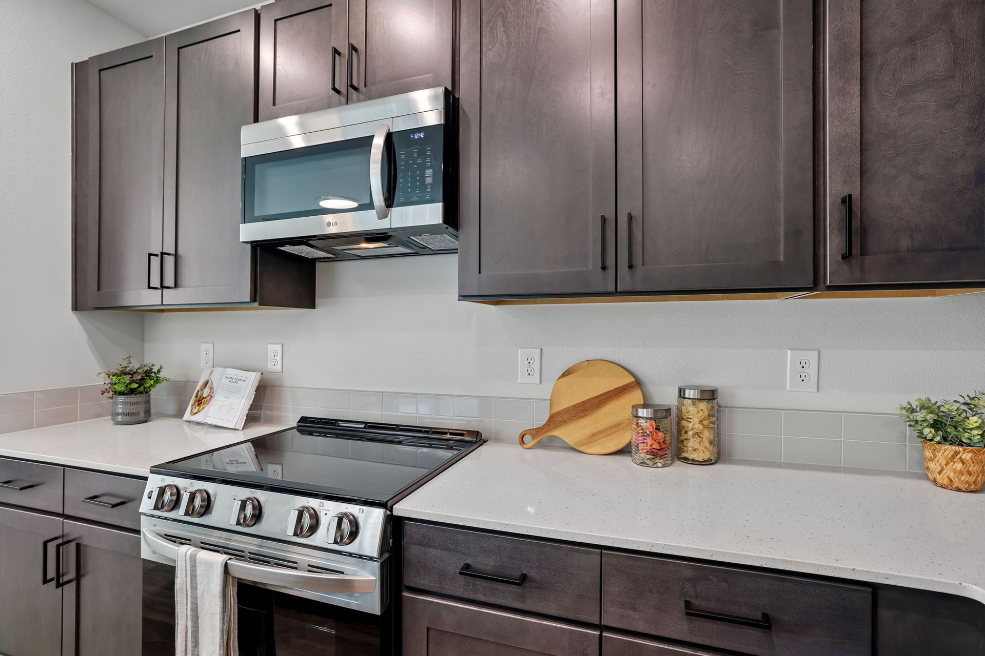 Modern kitchen with dark cabinets, white countertops, and stainless steel appliances