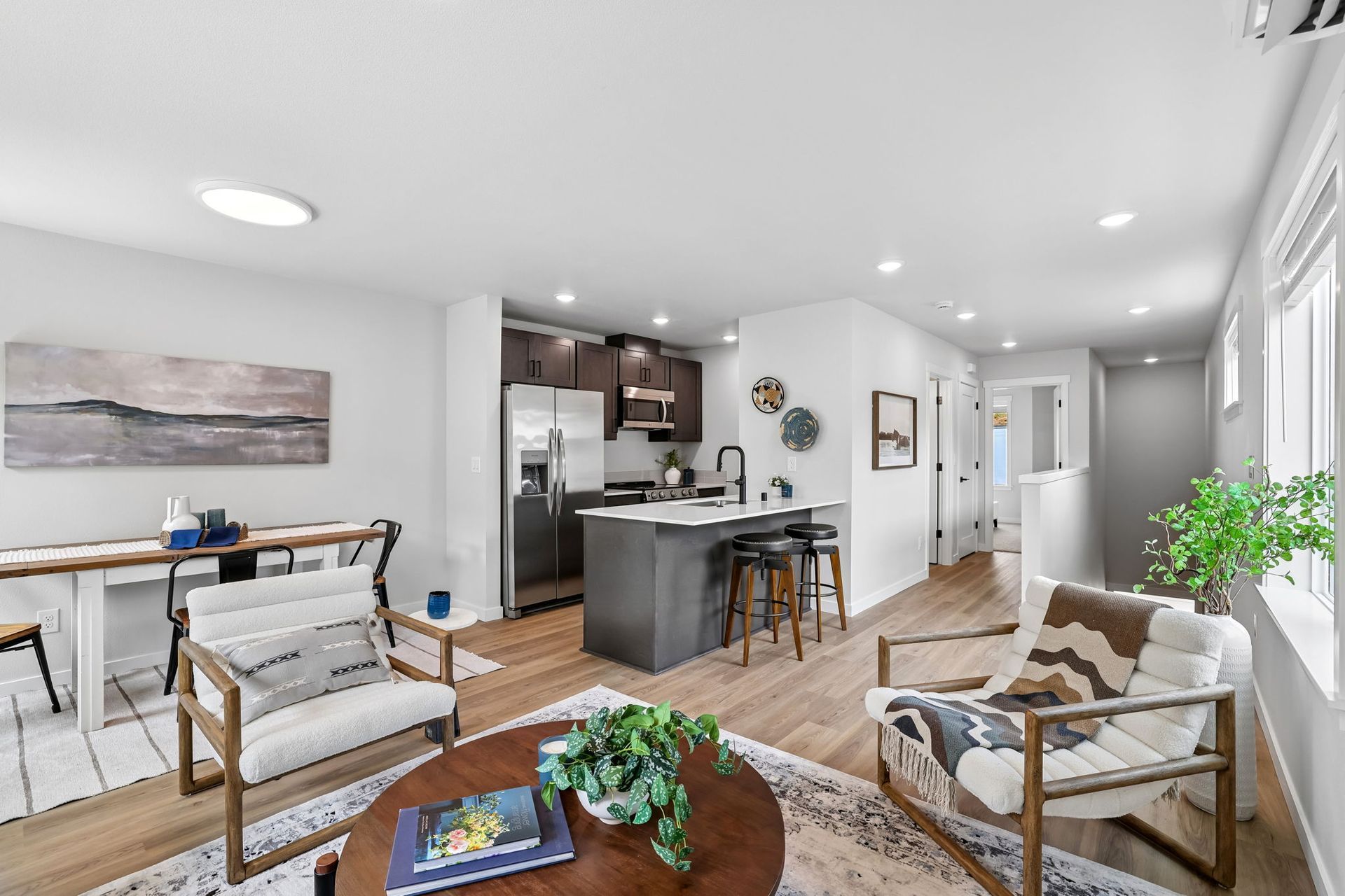 Bright modern living room and kitchen with gray chairs, wood floors, and a central island