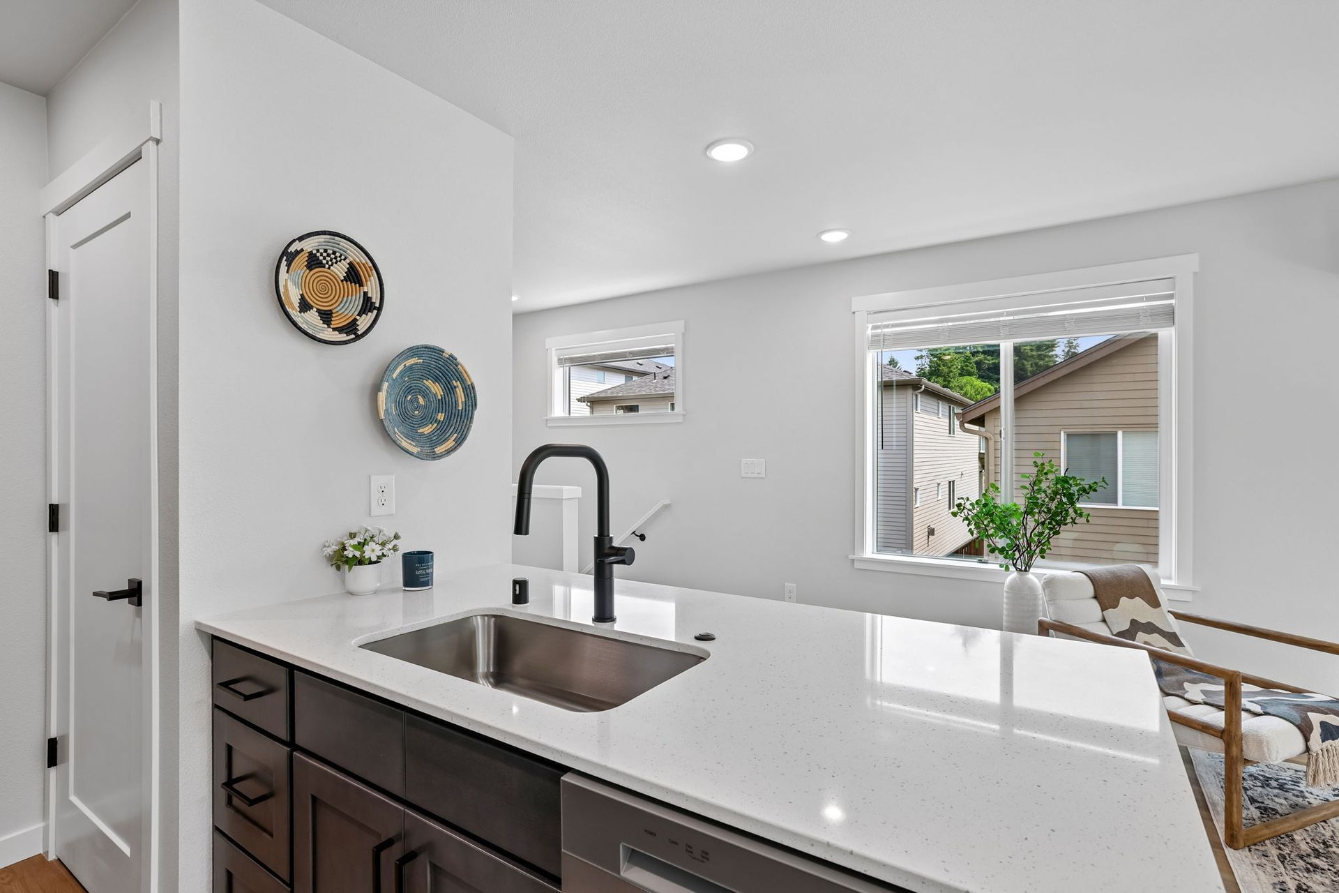 Bright kitchen with dark cabinets, white island, black faucet, and view of dining area and backyard through window.