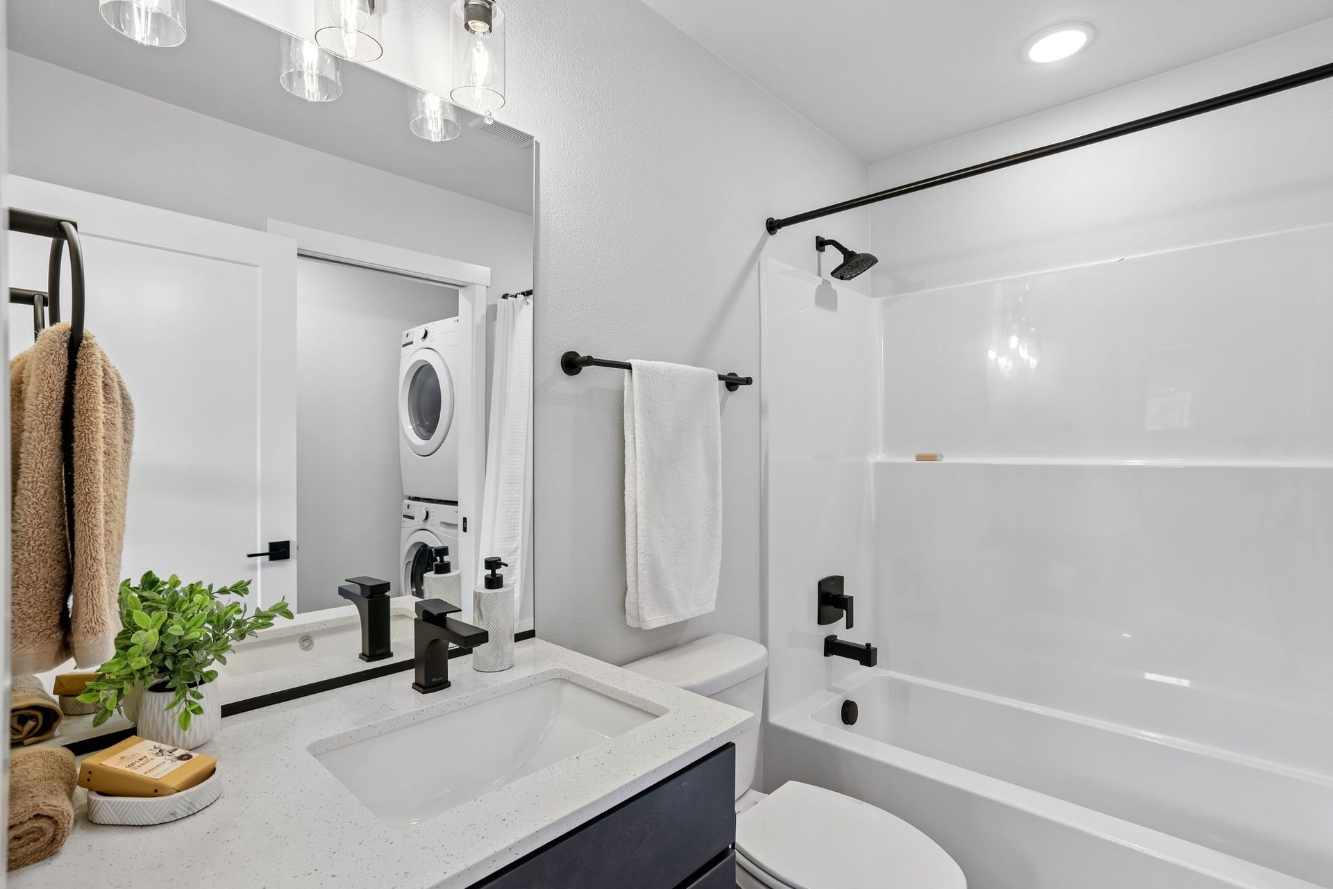 Bright modern bathroom with white shower, vanity, mirror, and black fixtures