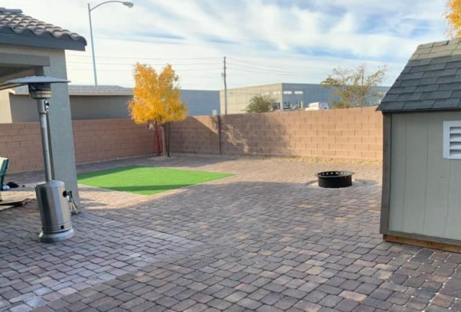 There is a brick walkway next to a lush green lawn.