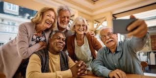 A group of elderly people are taking a selfie with a cell phone.