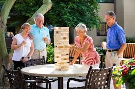 A group of elderly people are playing a game of jenga outside.